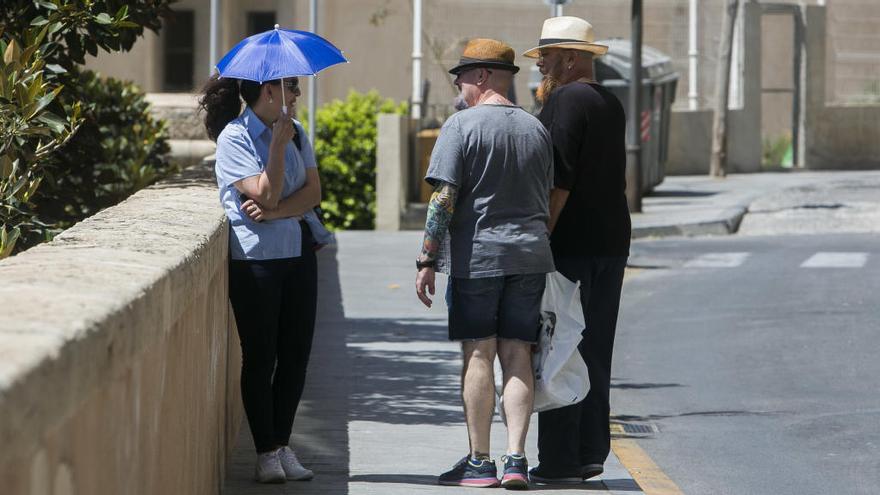 Tres personas charlan en la calle Virgen del Socorro de Alicante bien protegidas del sol