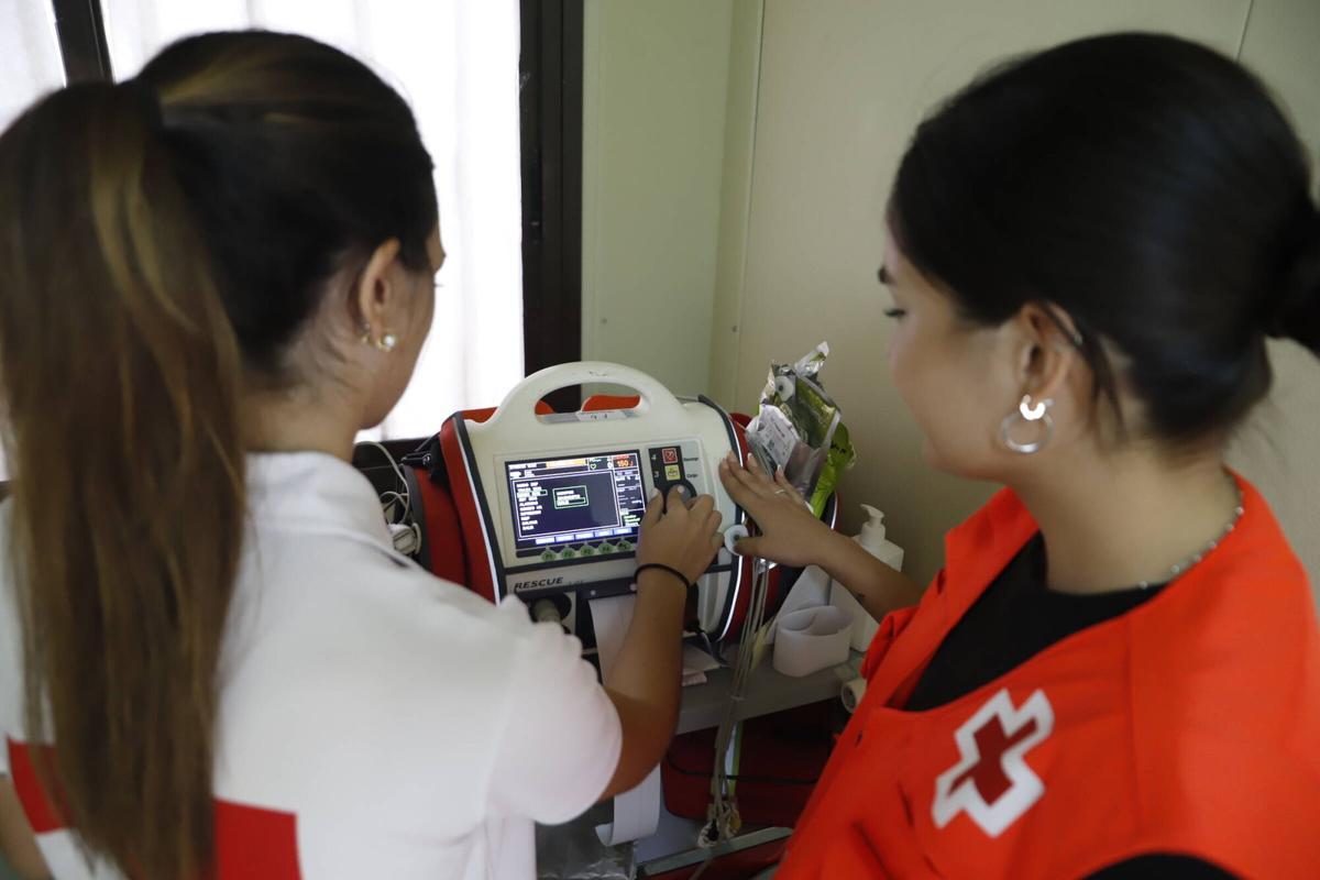 Dos voluntarias de Cruz Roja ajustan el equipo de soporte vital avanzado en la caseta.