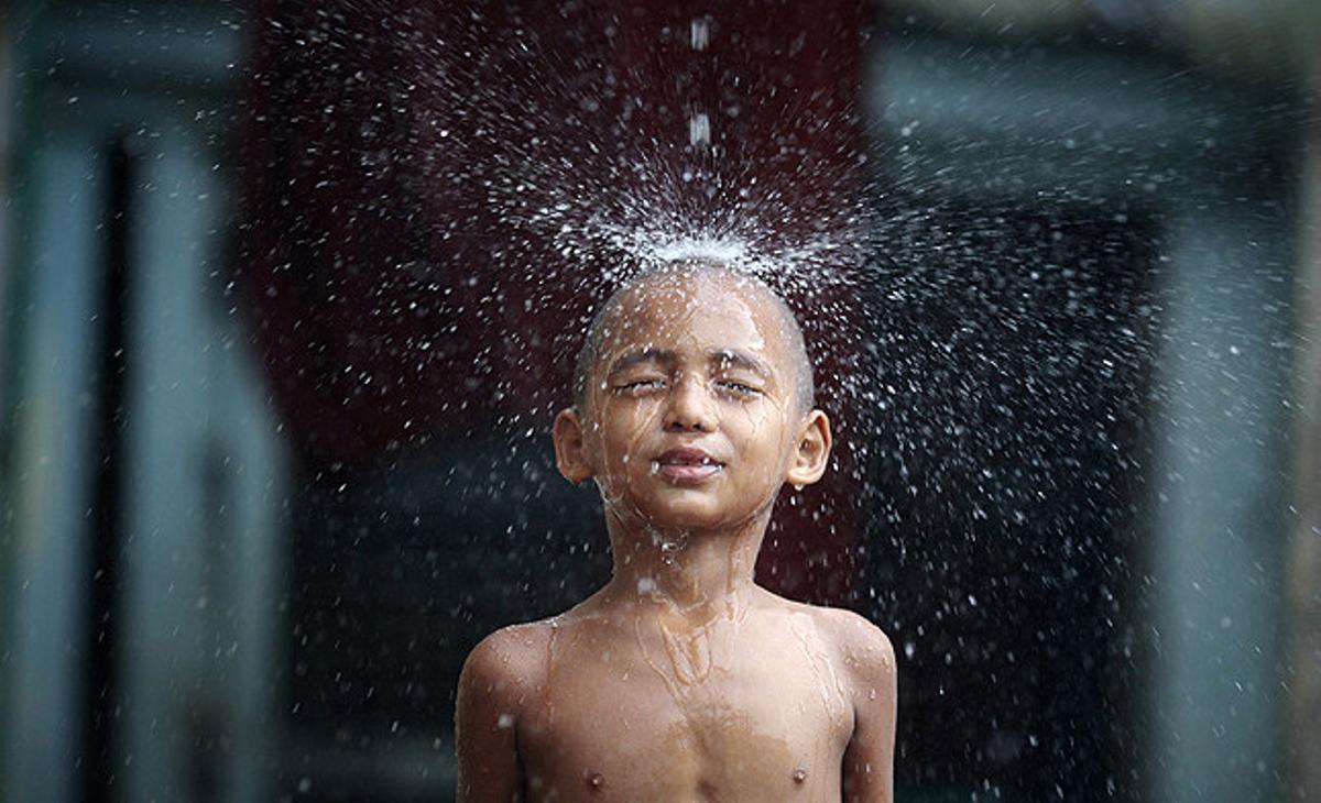 Un novici budista juga sota la pluja al monestir de Shin Ohtama Tharya, a Rangun (Birmània).