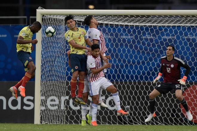 El colombiano Jefferson Lerma (L) encabeza el balón mientras el arquero paraguayo Roberto Fernández observa durante el partido de fútbol de la Copa América en el estadio Fonte Nova Arena en Salvador, Brasil.