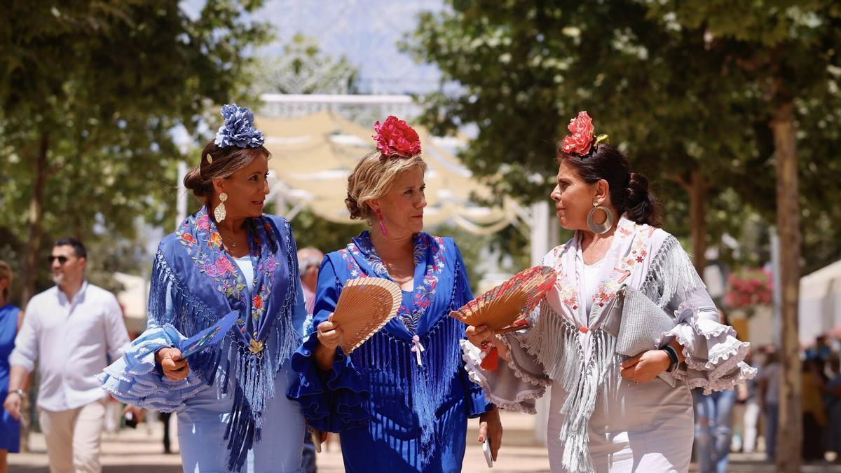 Tres mujeres pasean por la Feria de Córdoba, abanico en mano, este martes.