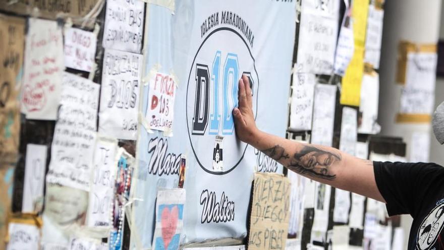 Un hombre toca una bandera frente a la clínica donde se encuentra internado Maradona