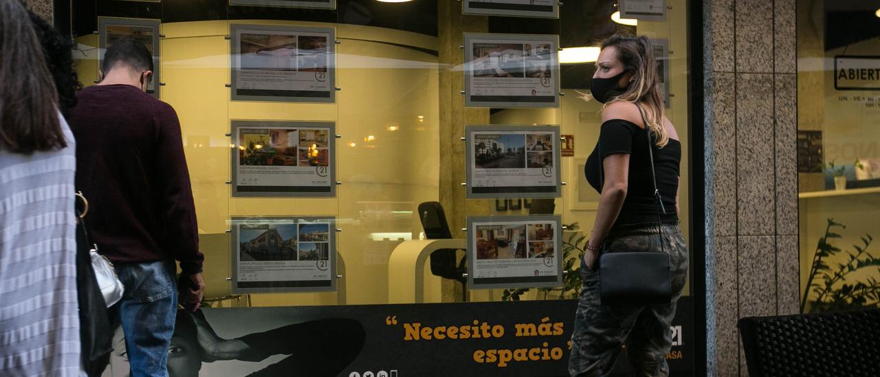 Una mujer frente al escaparate de una inmobiliaria.