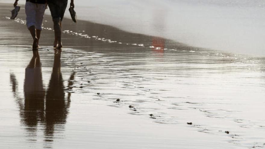 Una pareja pasea por la playa.