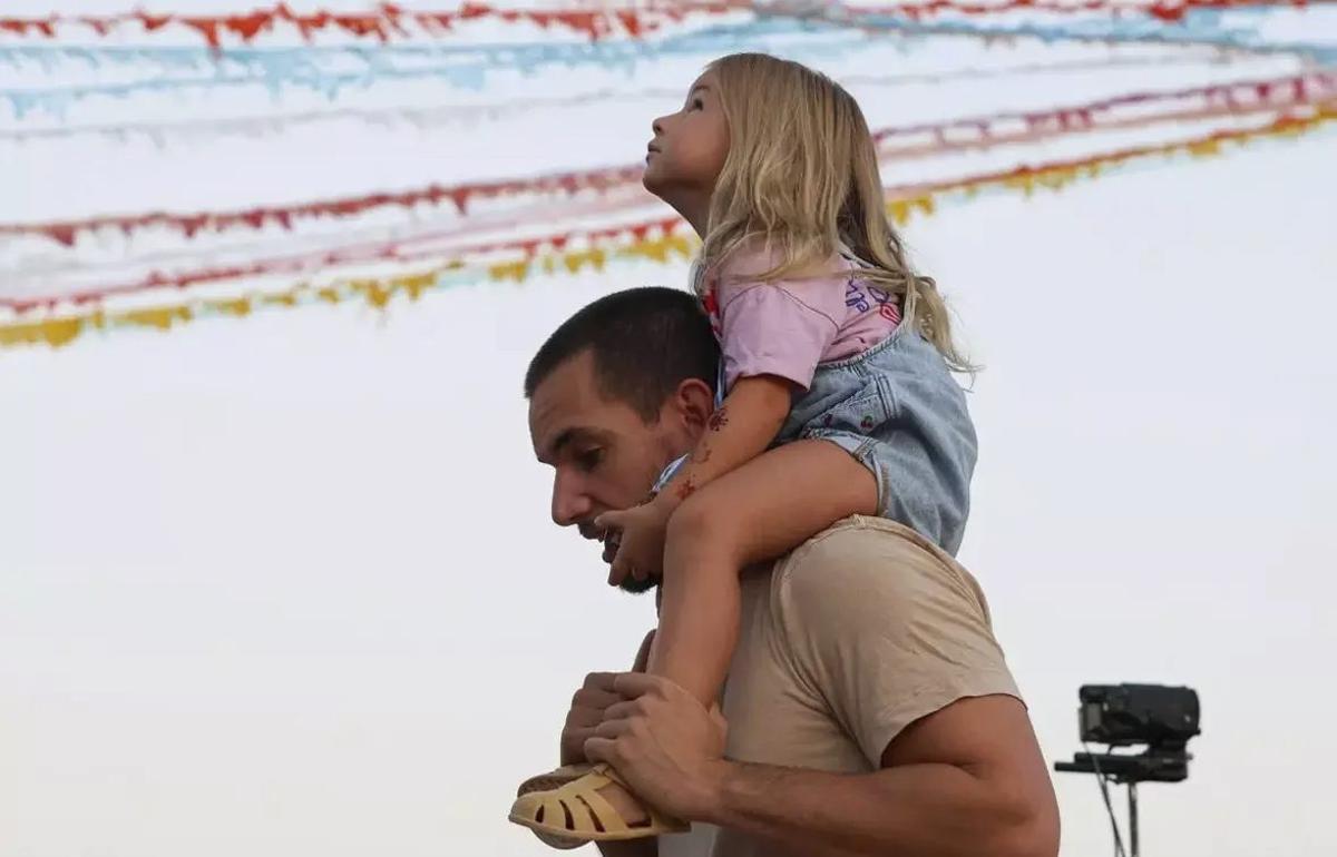 Una niña a hombros de su padre, en la plaza del pueblo.| Toni Escobar