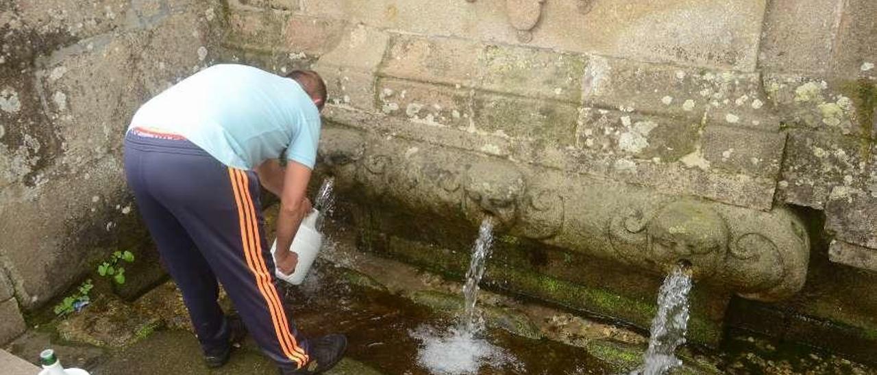 Un vecino toma agua en la fuente de Castroagudín, en Vilagarcía, ayer. // Noé Parga