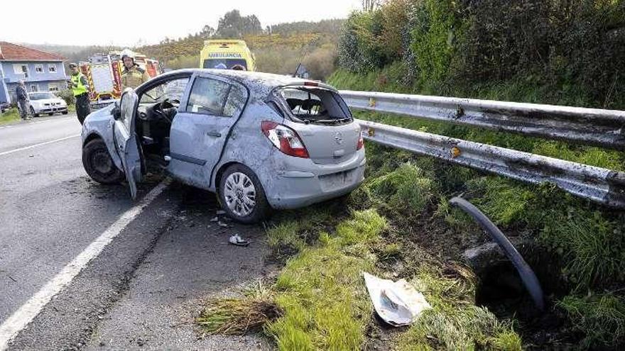 Un agente de Tráfico y bomberos, ayer, en el accidente que tuvo lugar por la mañana en la parroquia lalinense de Cadrón que se saldó con una vecina de Agolada herida. // Bernabé/Javier Lalín