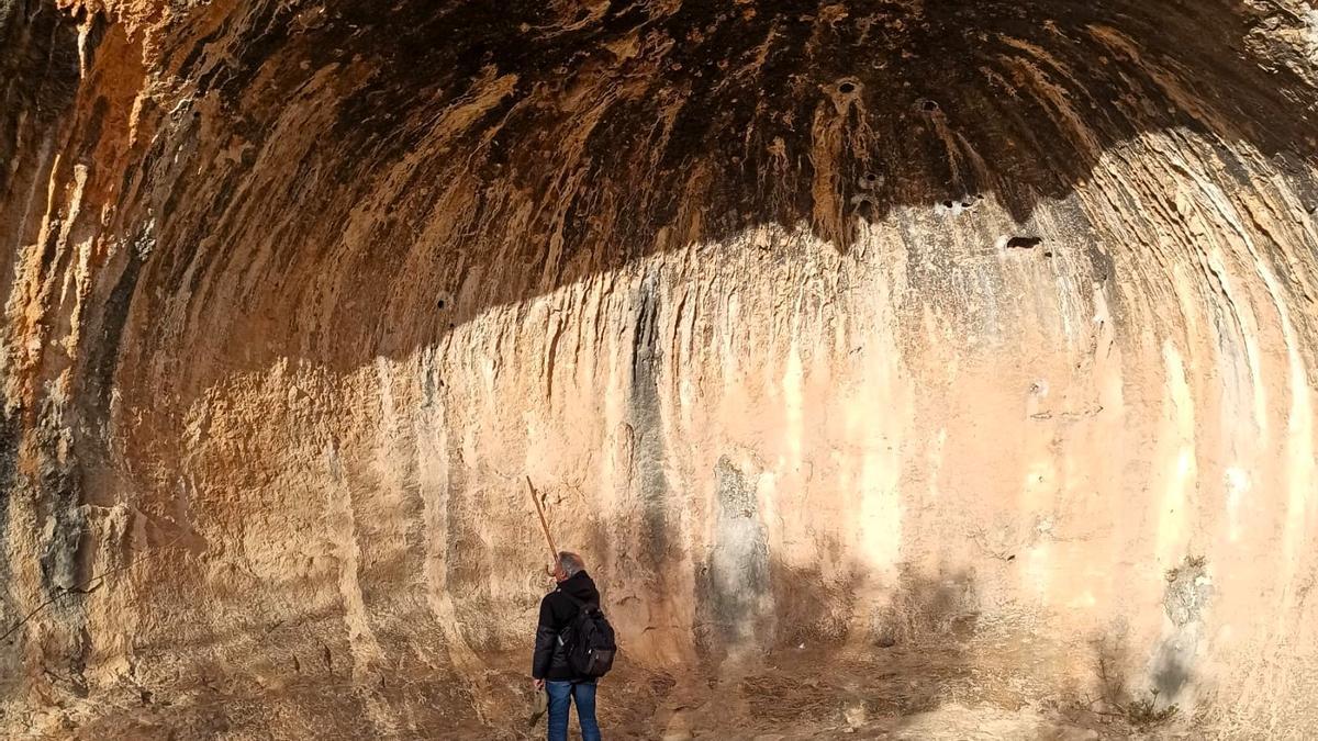 Pere Ferrer señala los restos de pintura rupestre ocultos en la Cova de la Petxina.