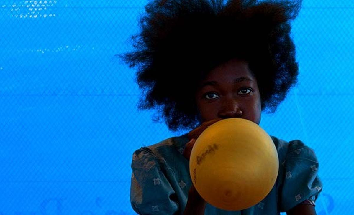 Virgilette, una noia de 15 anys que pateix símptomes de còlera, bufa un globus en una clínica de Port-au-Prince (Haití).