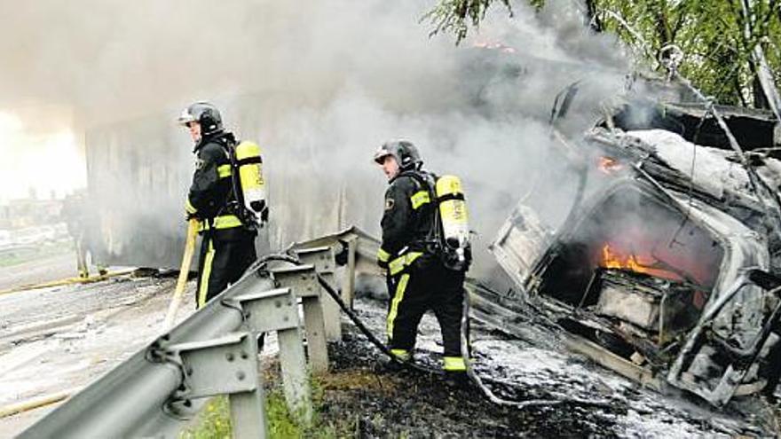 Los bomberos, durante las tareas de extinción del incendio del camión accidentado ayer al mediodía.