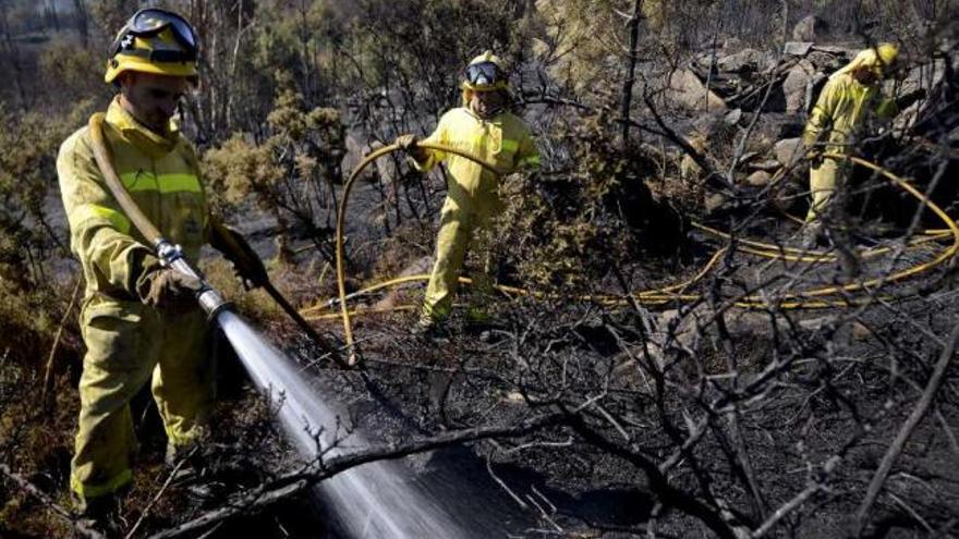 Tres brigadistas apagan los rescoldos en el incendio de Vilamarín, todavía por extinguir.  // Brais Lorenzo