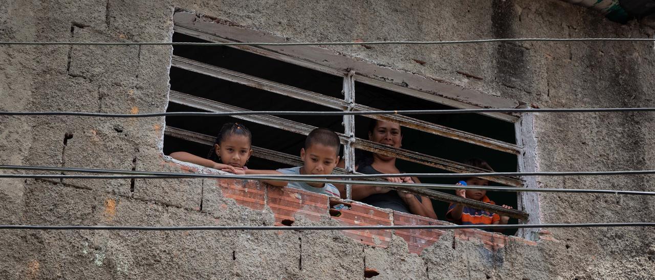 Una madre y sus hijos miran  por una ventana en la barriada de infraviviendas de Petare en la que la crisis social y económicas de Venezuela se agudiza.