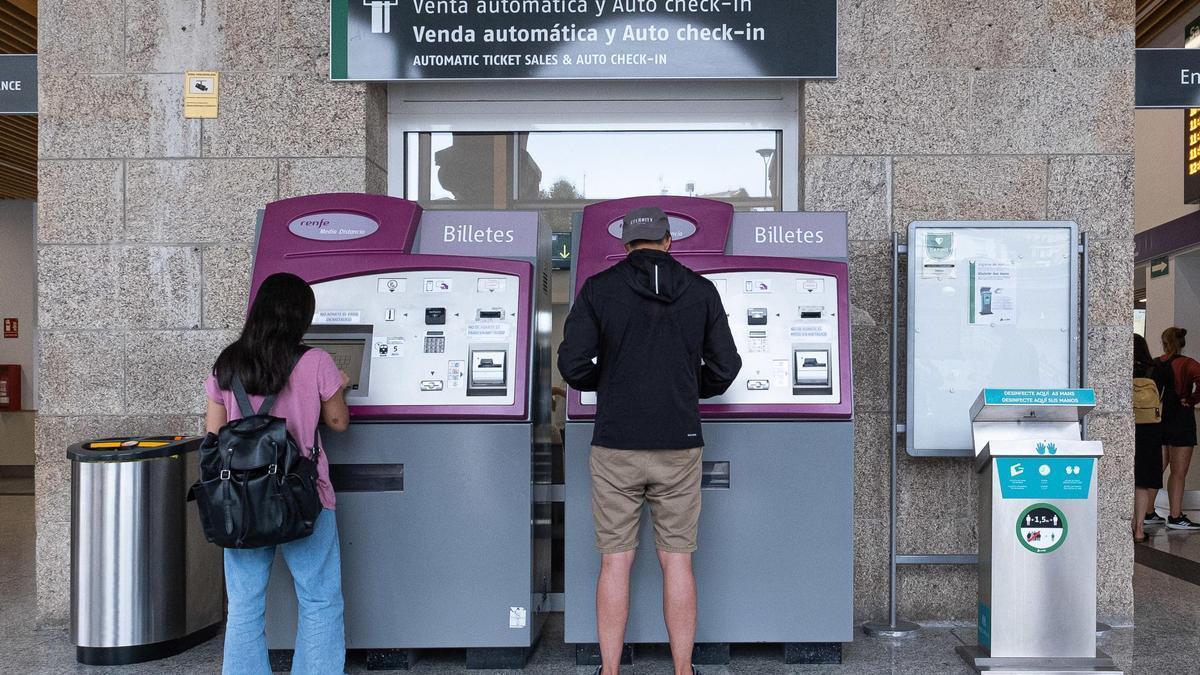 Dos viajeros compran billetes de tren en la estación de Santiago