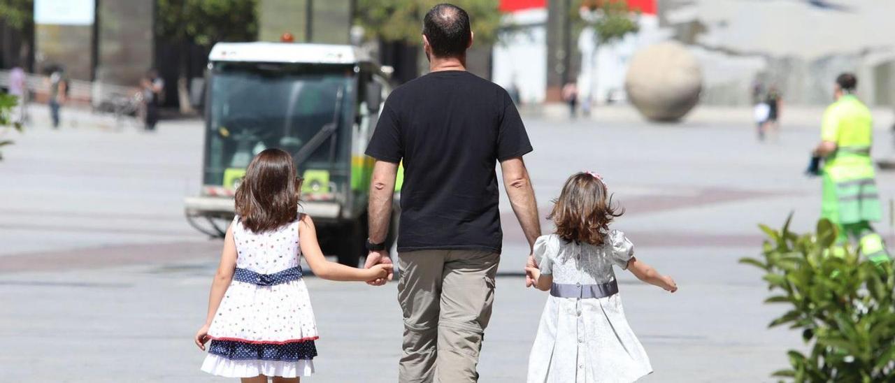 Un padre, paseando  con sus hijas.