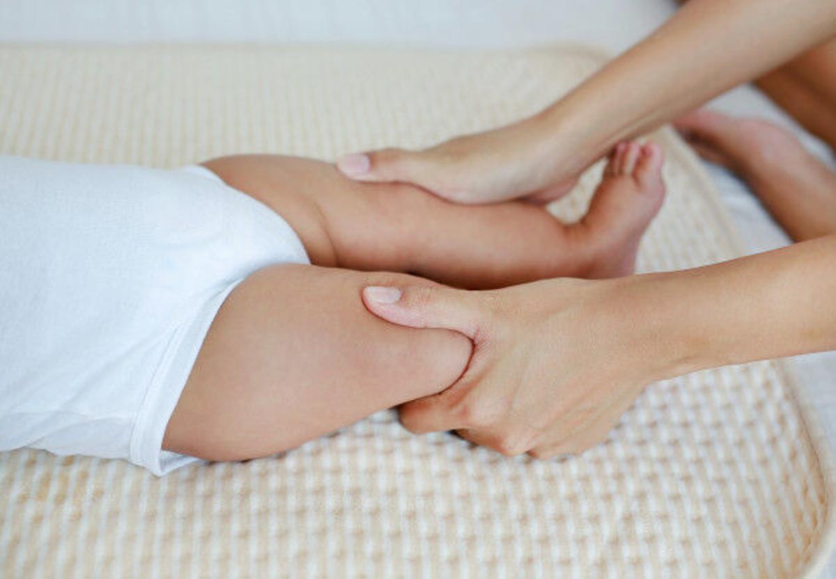 Una mujer coge las piernas de un bebé.