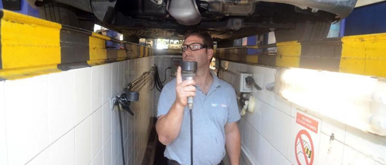 Un trabajador de la estación de ITV de Trabanca Badiña en el foso donde se comprueban los elementos de los bajos del coche.