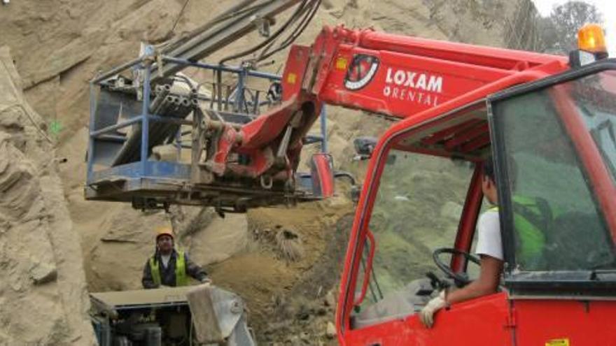 Dos trabajadores realizan tareas de consolidación del talud en el término municipal de Arrabalde.