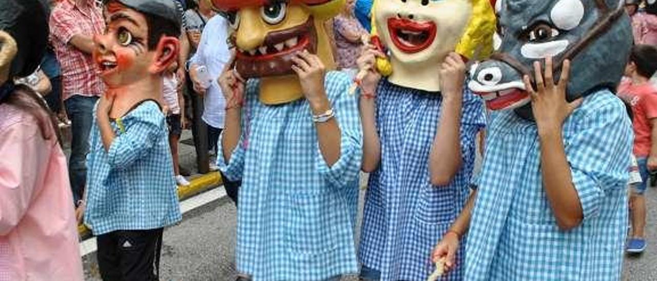 Tres jóvenes con caretas y el chambrón de San Timoteo; a la derecha, la charanga &quot;BB+&quot;, durante el desfile.