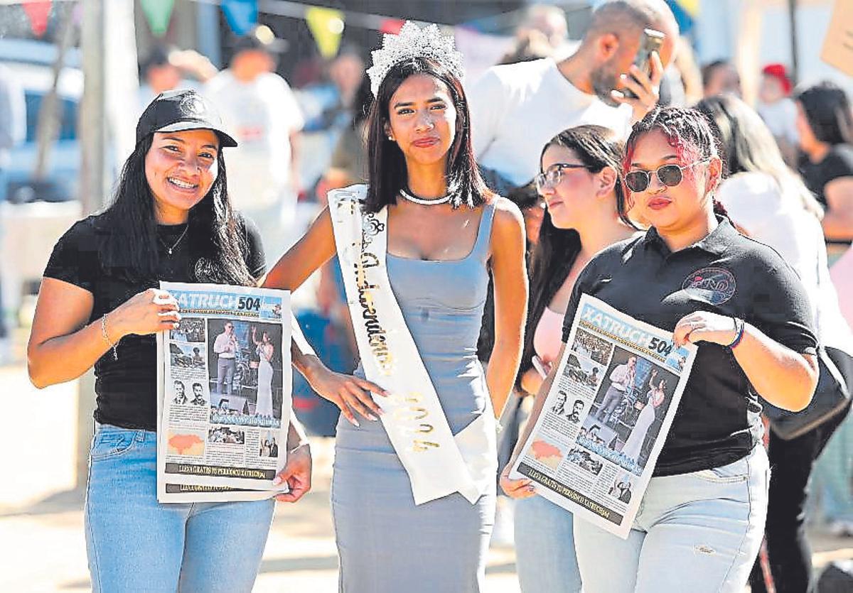 Dues dones, mostrant la revista «Xatruch 504» durant una celebració de la comunitat hondurenya a Girona.