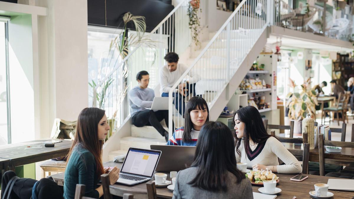 Jóvenes empresarias que trabajan a distancia reuniéndose en una mesa de café
