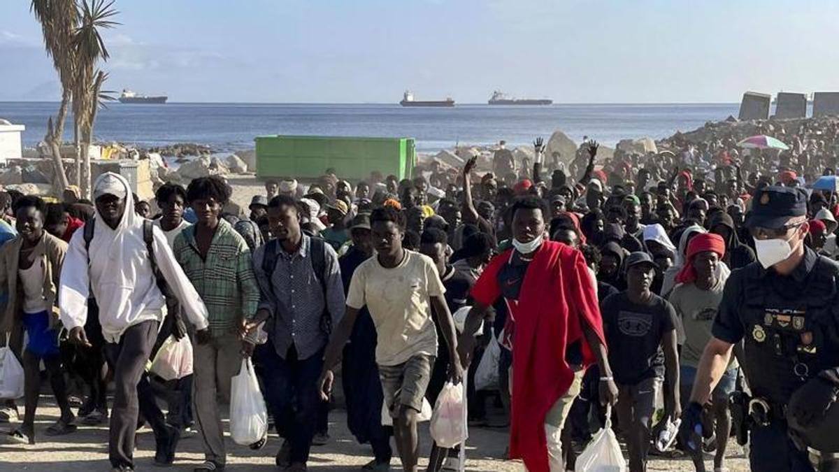 Cerca de 1.700 migrantes dejan la playa ceutí del Trampolín escoltados por la Policía.