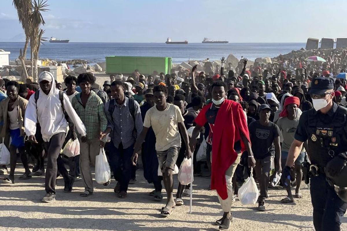 Cerca de 1.700 migrantes dejan la playa ceutí del Trampolín escoltados por la Policía.