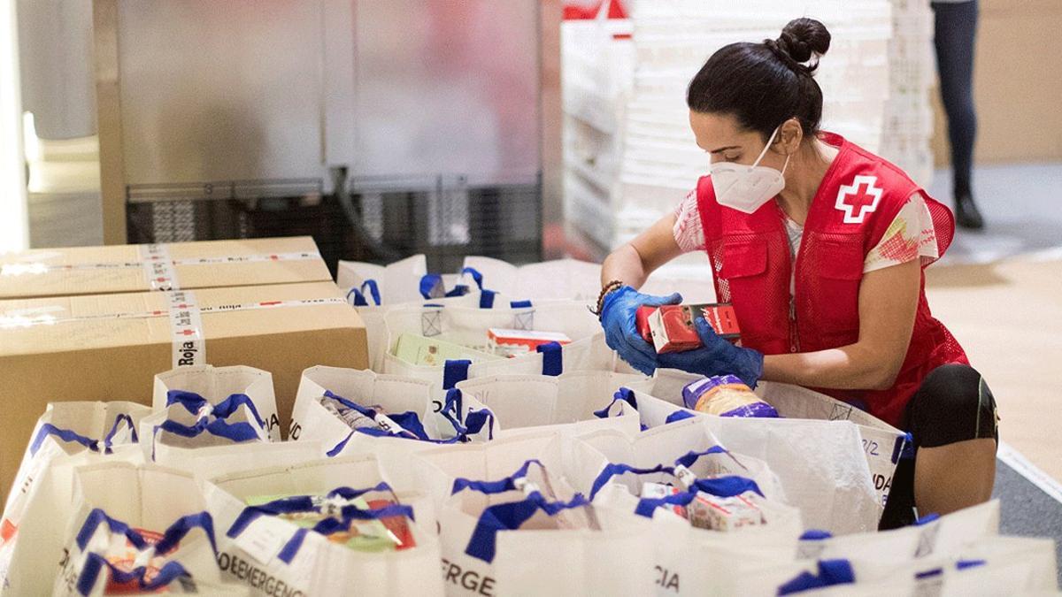 Una voluntaria prepara paquetes de alimentación básica en el almacén de la Cruz Roja en Barcelona, el 6 de mayo