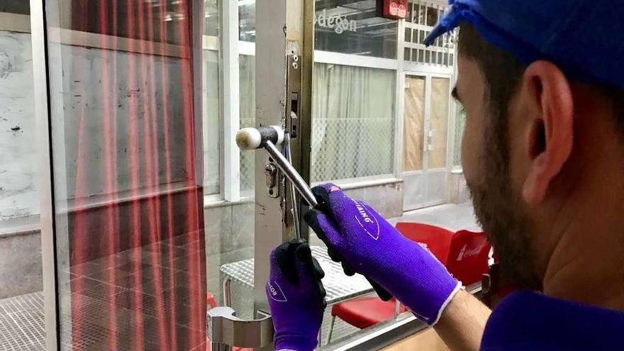 Trabajadores arreglan la puerta forcejeada del local Os Nosos Amigos de Lalín. // Bernabé