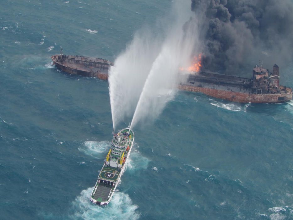 A rescue ship works to extinguish the fire on ...