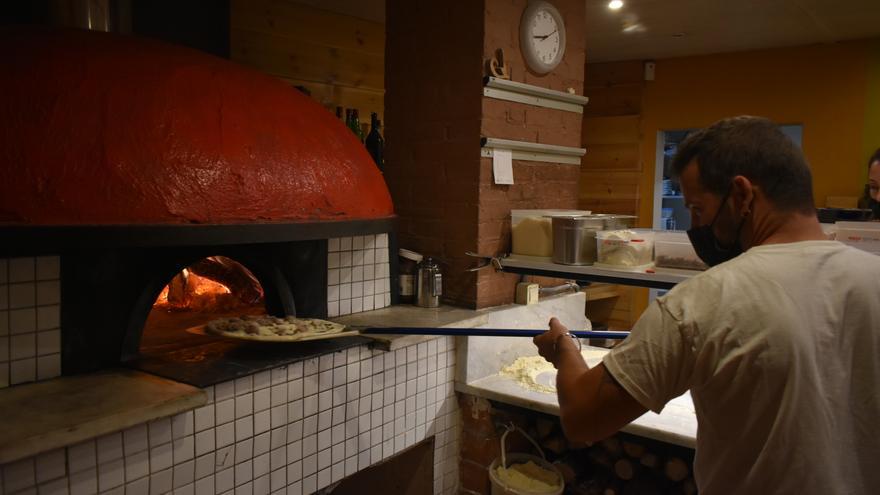 Jordi López posant una pizza al forn