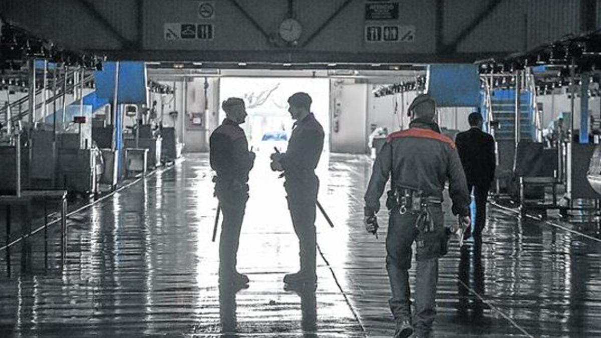 Una inspectora de la Agencia Tributaria , acompañada por un mossos de esquadra, ayer en el mercado central de pescado de Marcabarna.