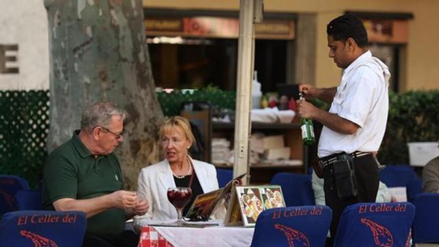 Un camarero atiende a unos clientes en establecimiento de Barcelona.