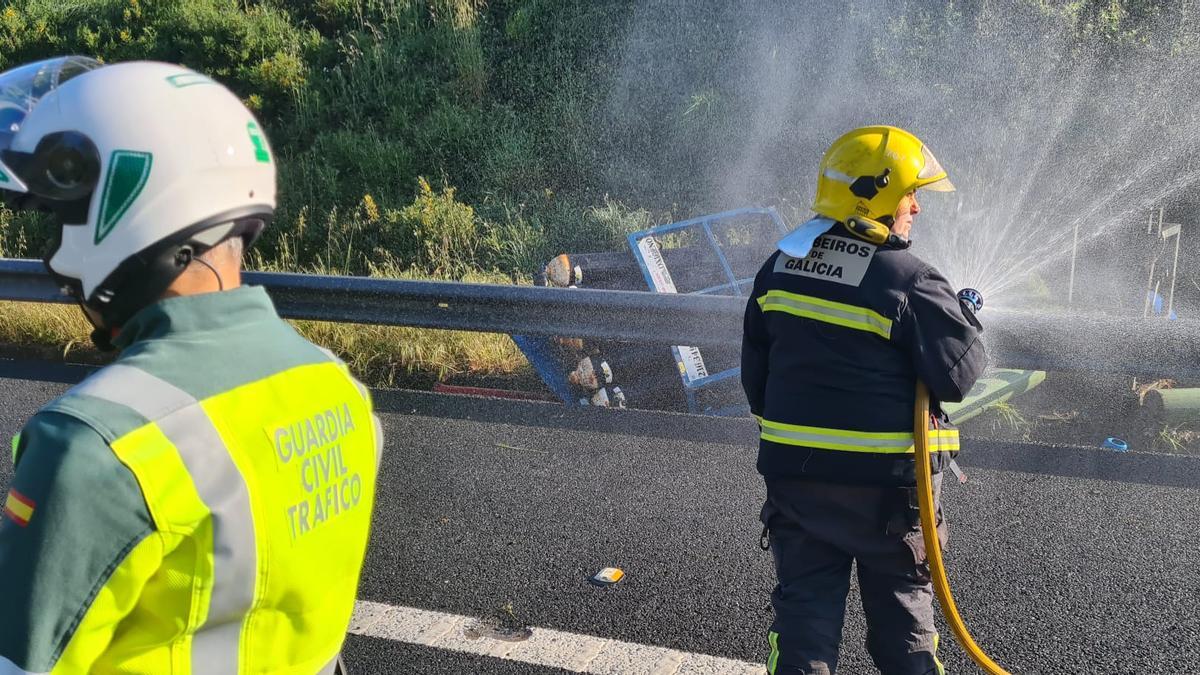 Efectivos de emergencias enfrían las bombonas de acetileno que cayeron del camión accidentado.