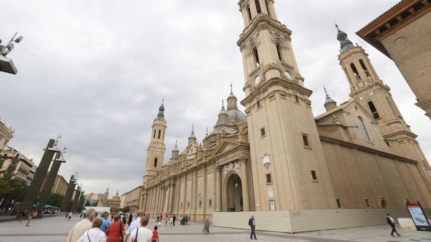 Zaragozanos y turistas, este jueves en la plaza del Pilar, con las torres ya valladas.
