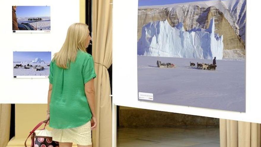 Una asistente a la exposición observa varias fotografías de la muestra.