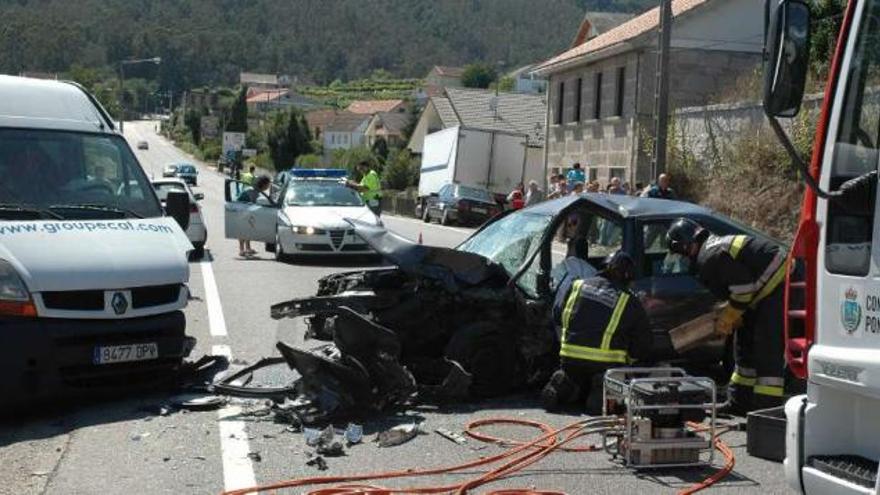 Los bomberos tratan de excarcelar el cuerpo del fallecido entre los hierros del vehículo. / d.p.