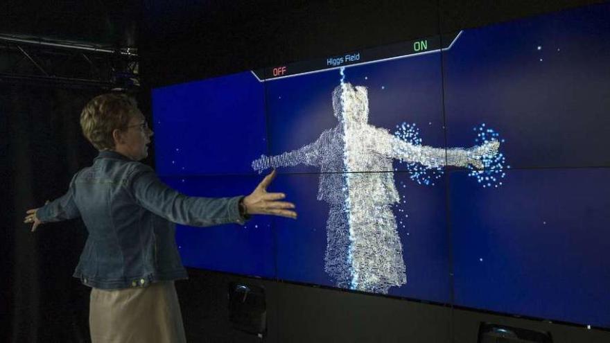 Una mujer contempla la representación de su figura en la pantalla formada por las partículas.