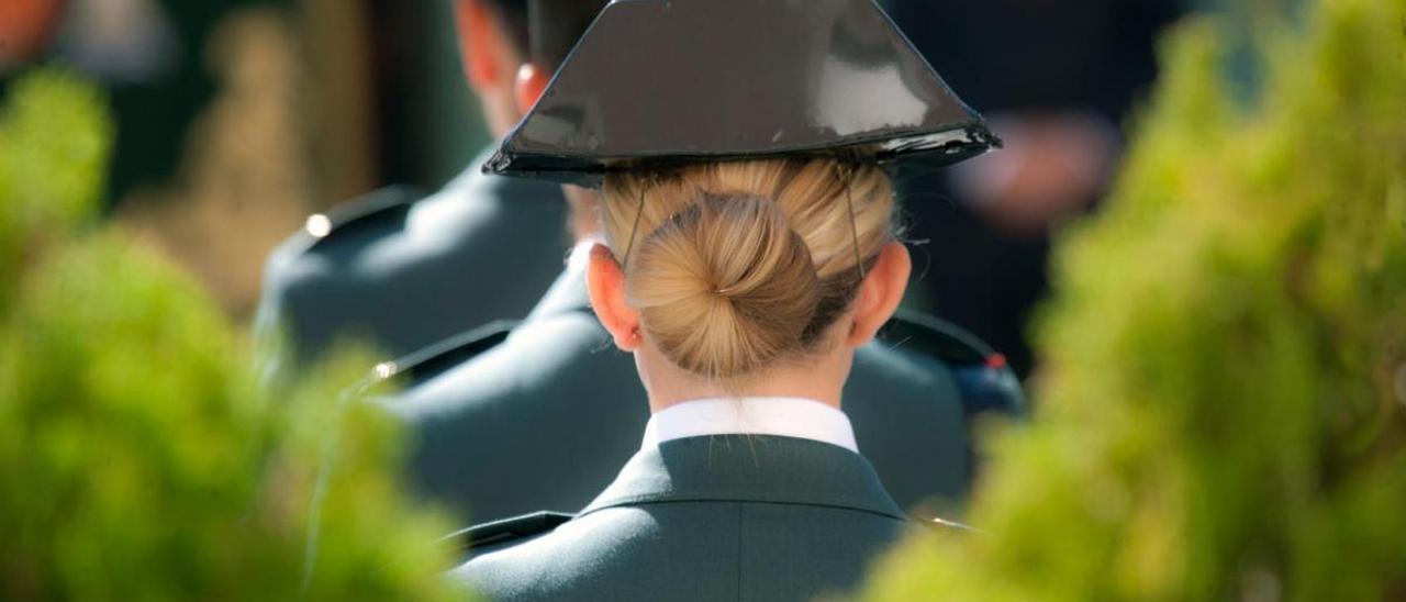 Una mujer, agente de la Guardia Civil, con el tricornio y el uniforme junto a compañeros.