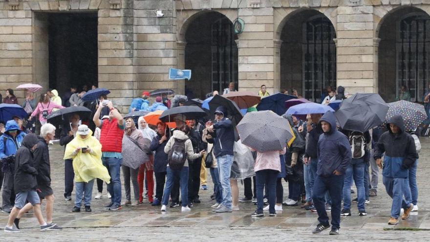 Un grupo de turistas bajo la lluvia en el Obradoiro. En lo que va de año ya se han recogido más de 1.800 litros por metro cuadrado / A. HERNÁNDEZ