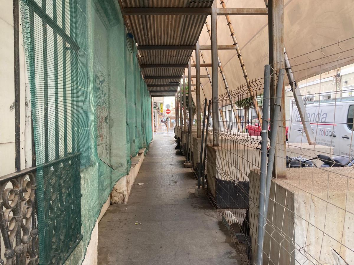 Acera sobre la que están dispuestos los andamios y una red en la fachada para proteger de la caída de cascotes