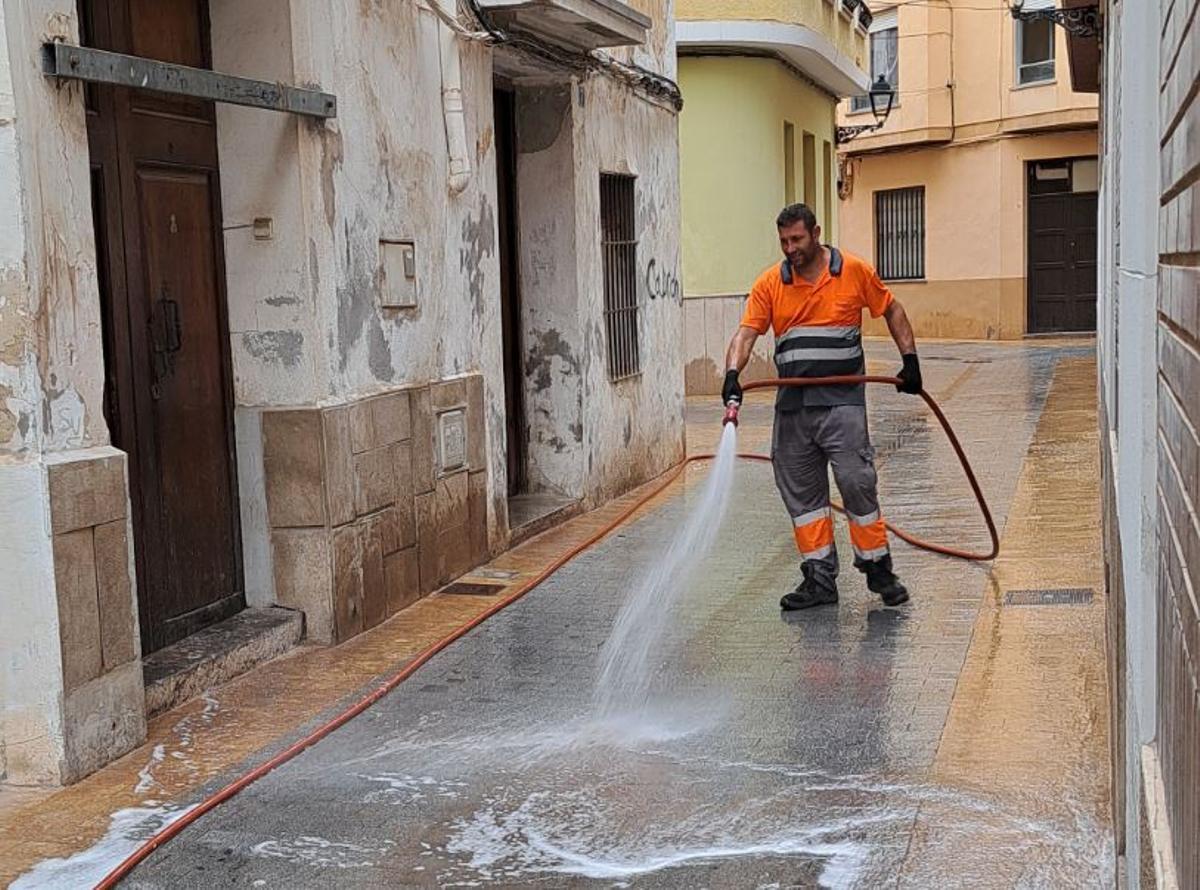 Un operario limpia con una manguera en una calle céntrica de la ciudad