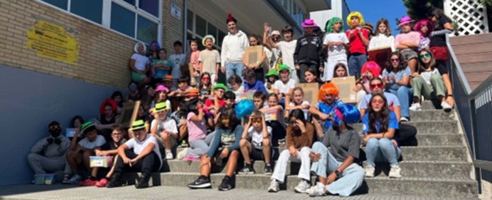 Alumnos de quinto de Primaria posan nas escaleiras do colexio con material doado pola ANPA.