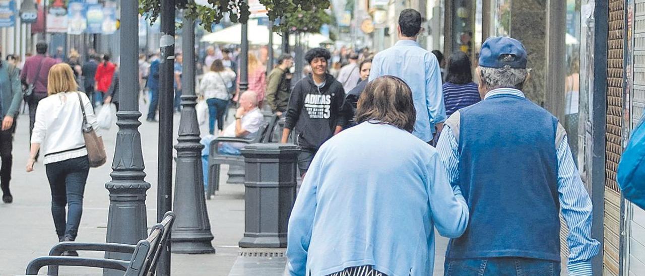 Dos personas mayores pasean por la calle Mayor de Triana.