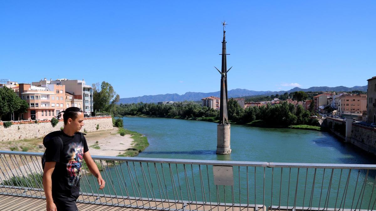 Un ciutadà travessa el pont de l'Estat de Tortosa davant del monument franquista de l'Ebre