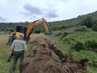 Los agentes forestales abren una zanja para enterrar a los peces muertos en Arrolobos