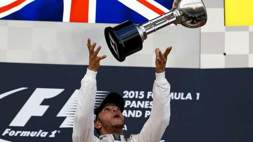 Lewis Hamilton juguetea con el trofeo de ganador en el podio. // Thomar Peter