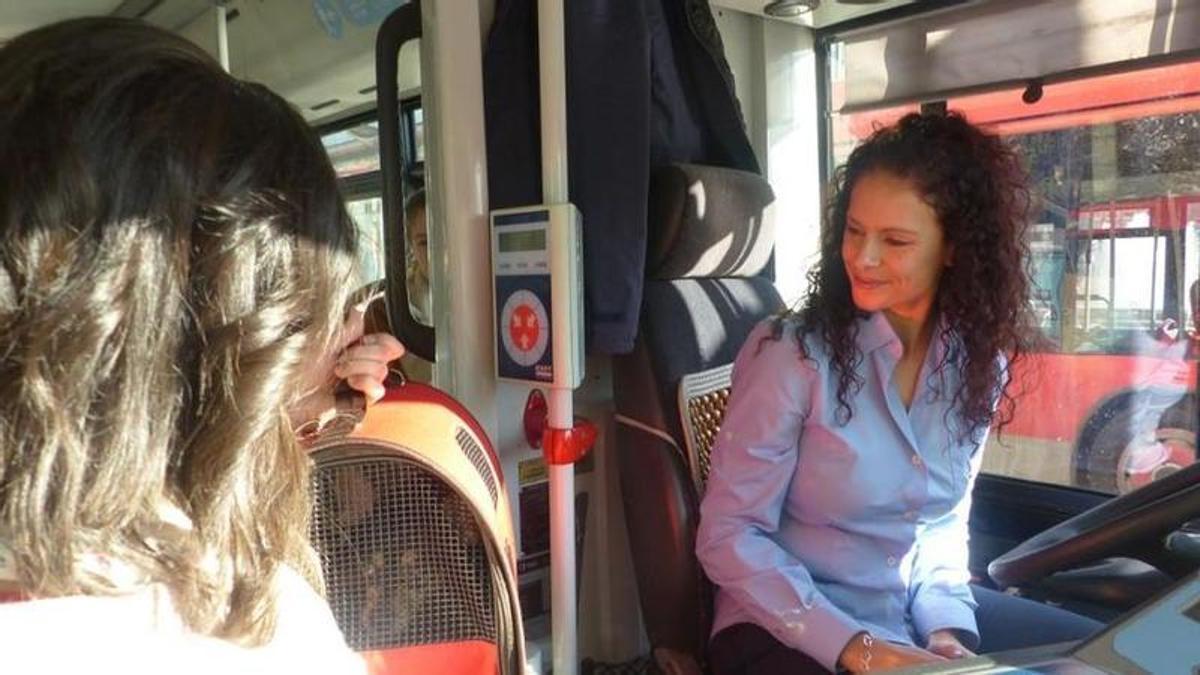 Una mujer sube con su mascota en un transportín al autobús.