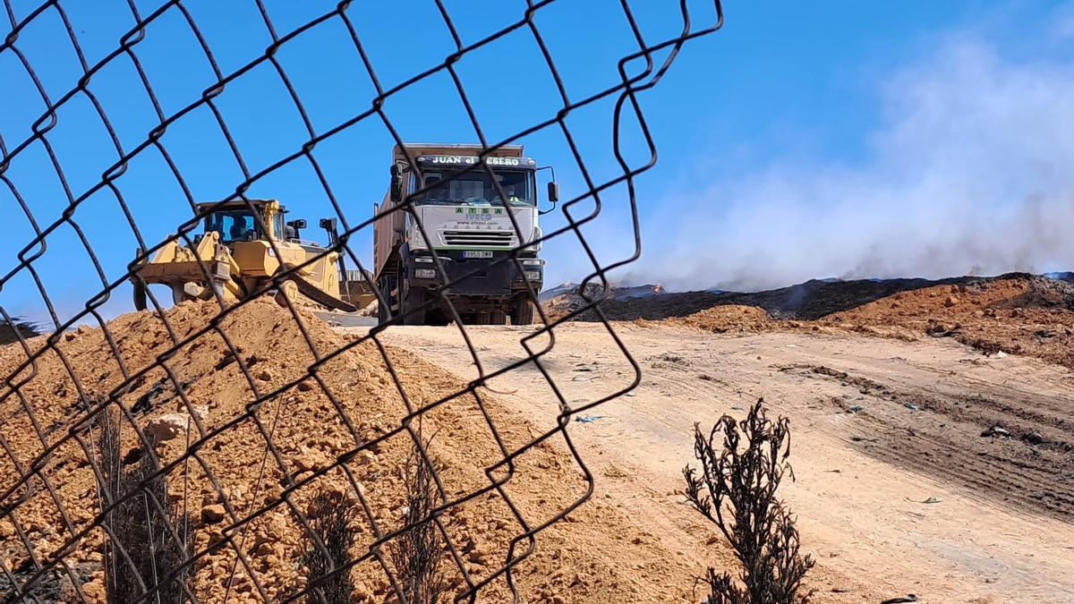 Excavadoras y camiones trabajando esta mañana en la planta de reciclaje de Requena cuyo incendio lleva activo más de diez días.