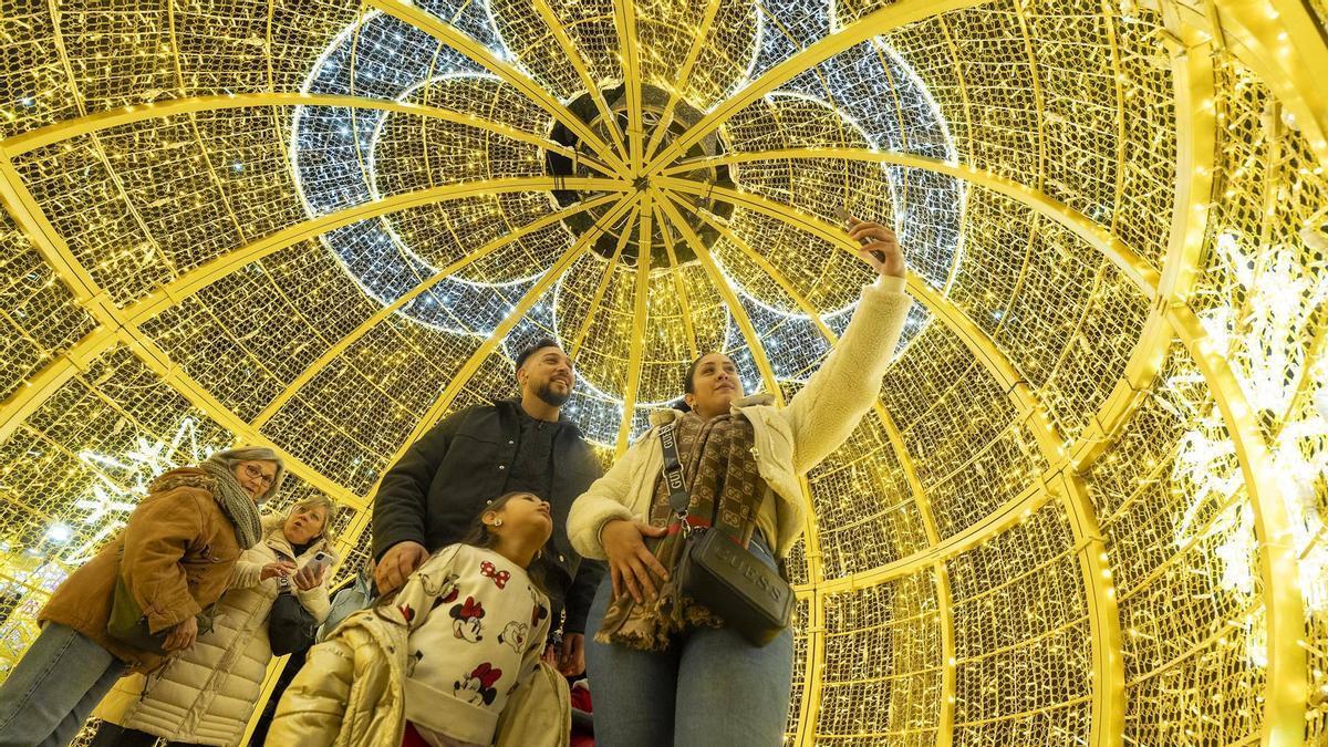 Una familia debajo de un adorno navideño.