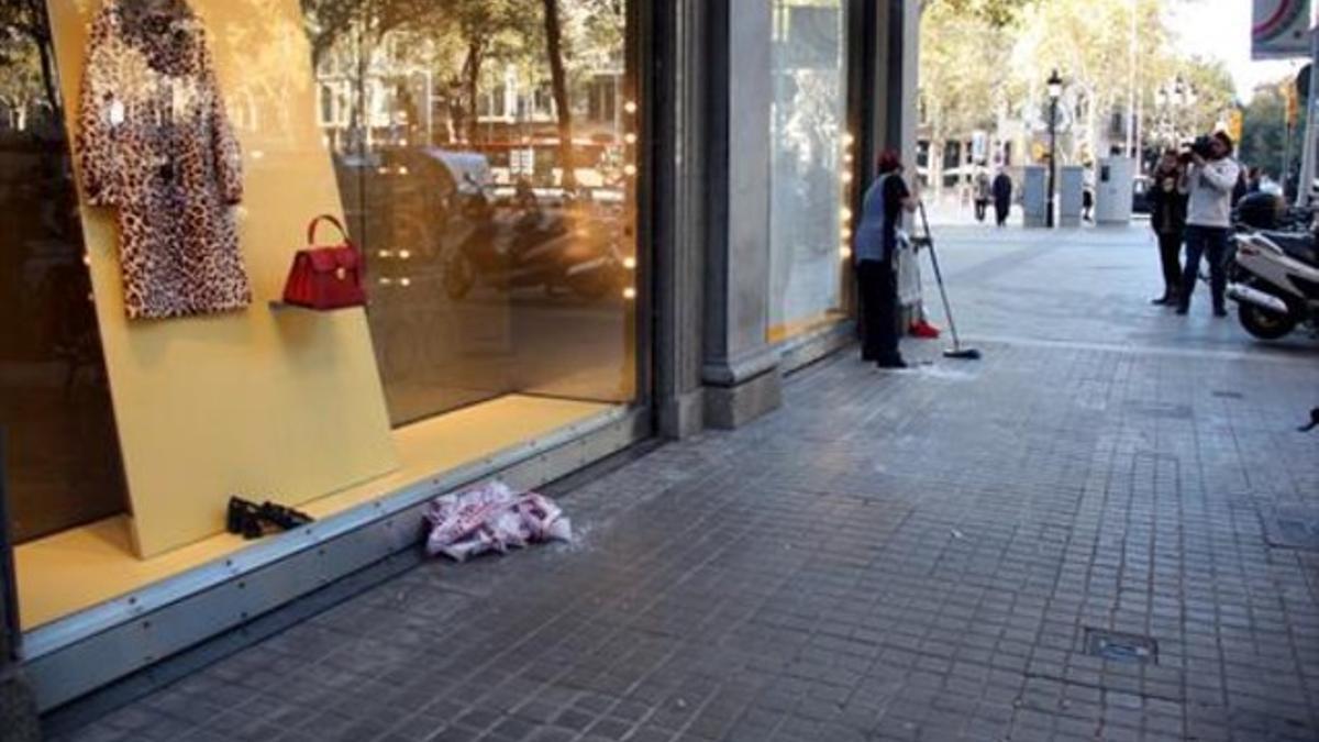 Una mujer barre los cristales rotos del escaparate de la tienda Miu Miu, ayer por la mañana.